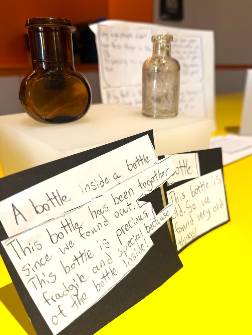 bottle artefacts and handwritten descriptions displayed on a table