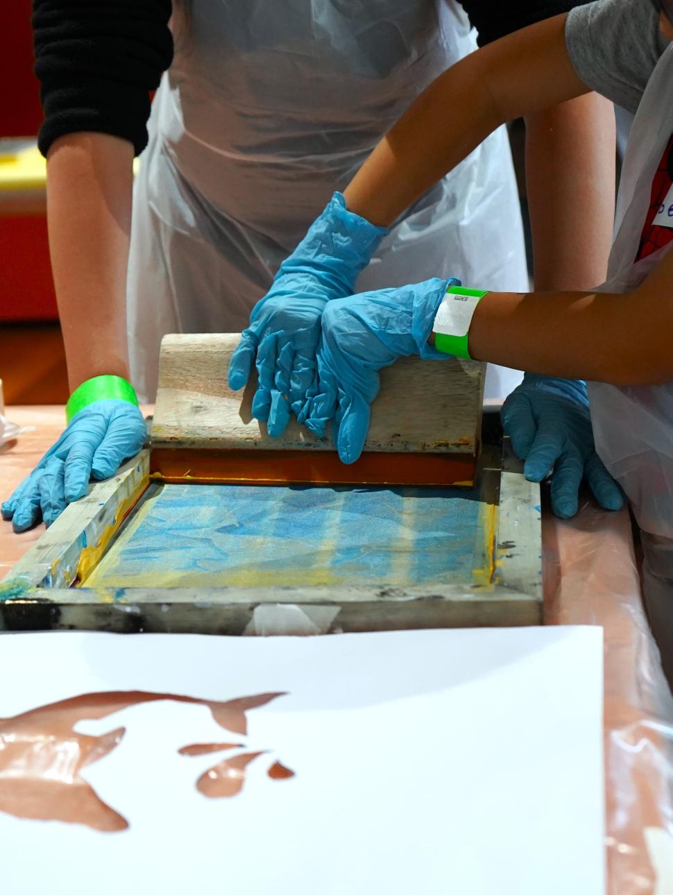 children screen printing a dolphin stencil at a table