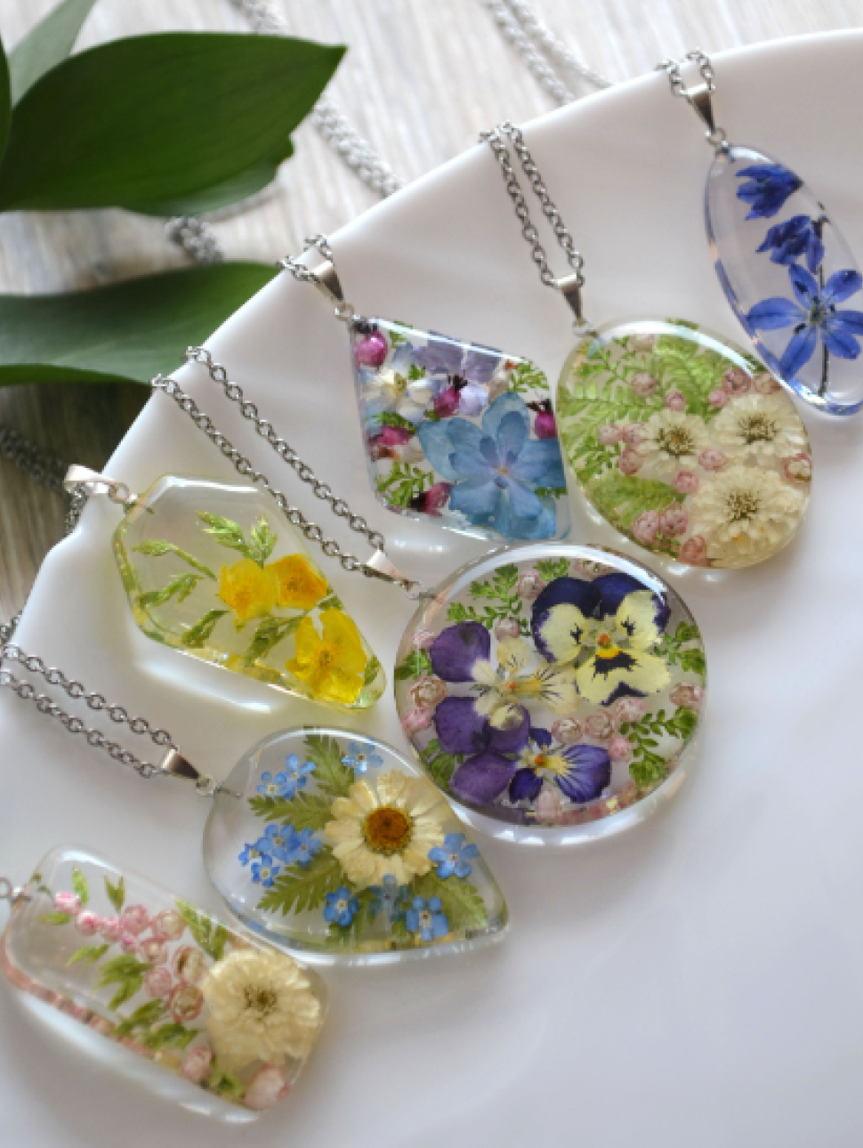 a view of a collection of six pendant resin jewellery with flowers and leaves in the art piece
