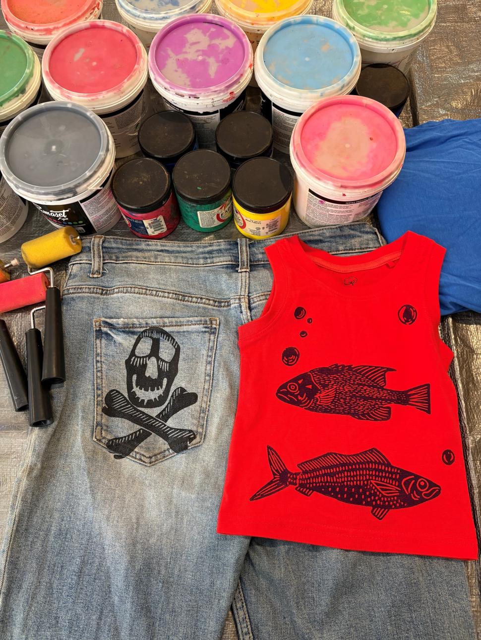 paint cans next to some clothing with prints on them from the paints