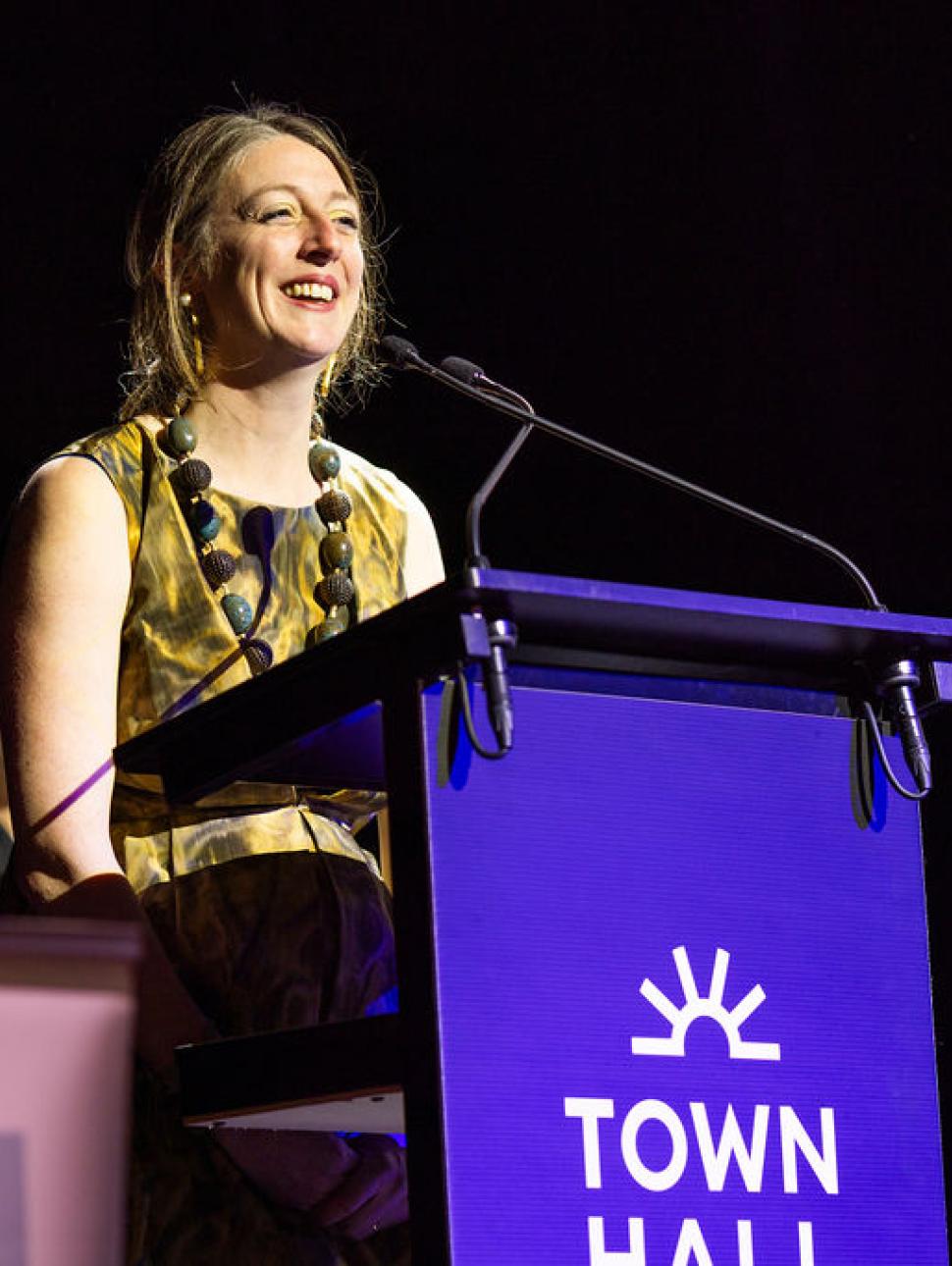 A blonde haired woman speaks at a podium