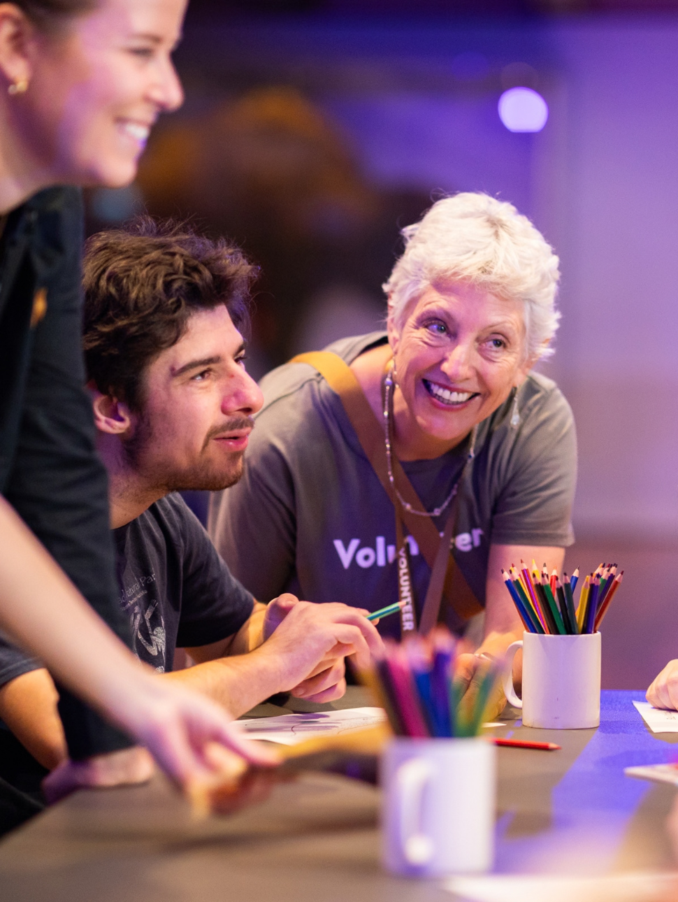 Museum Volunteer helping a person with disability seated at a table