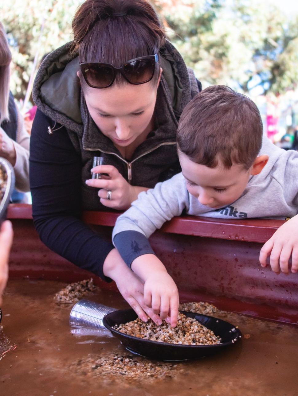 Mother and son shift through dirt to find gold