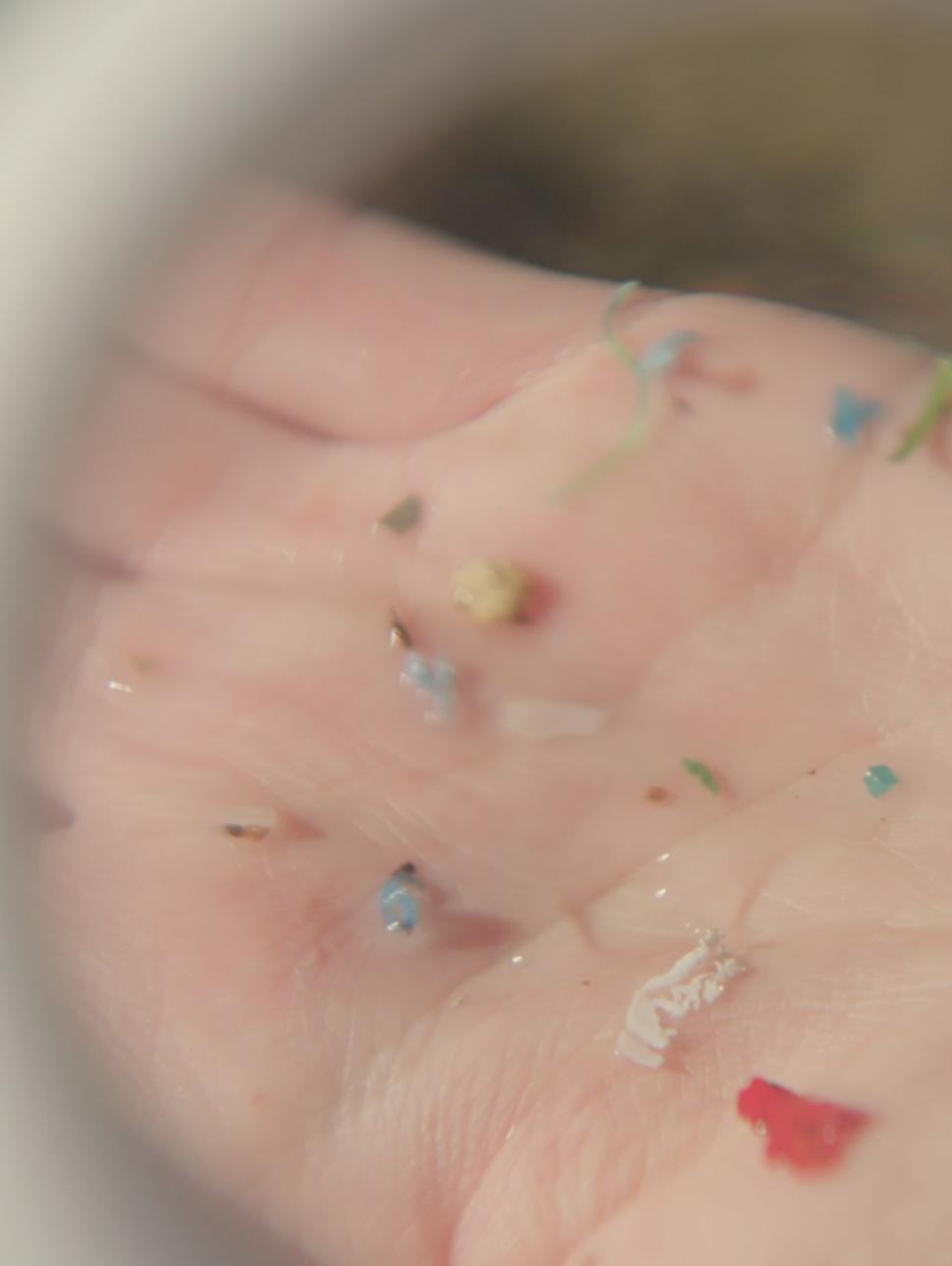 Palm of someone's hand displaying tiny pieces of multi-coloured plastic 