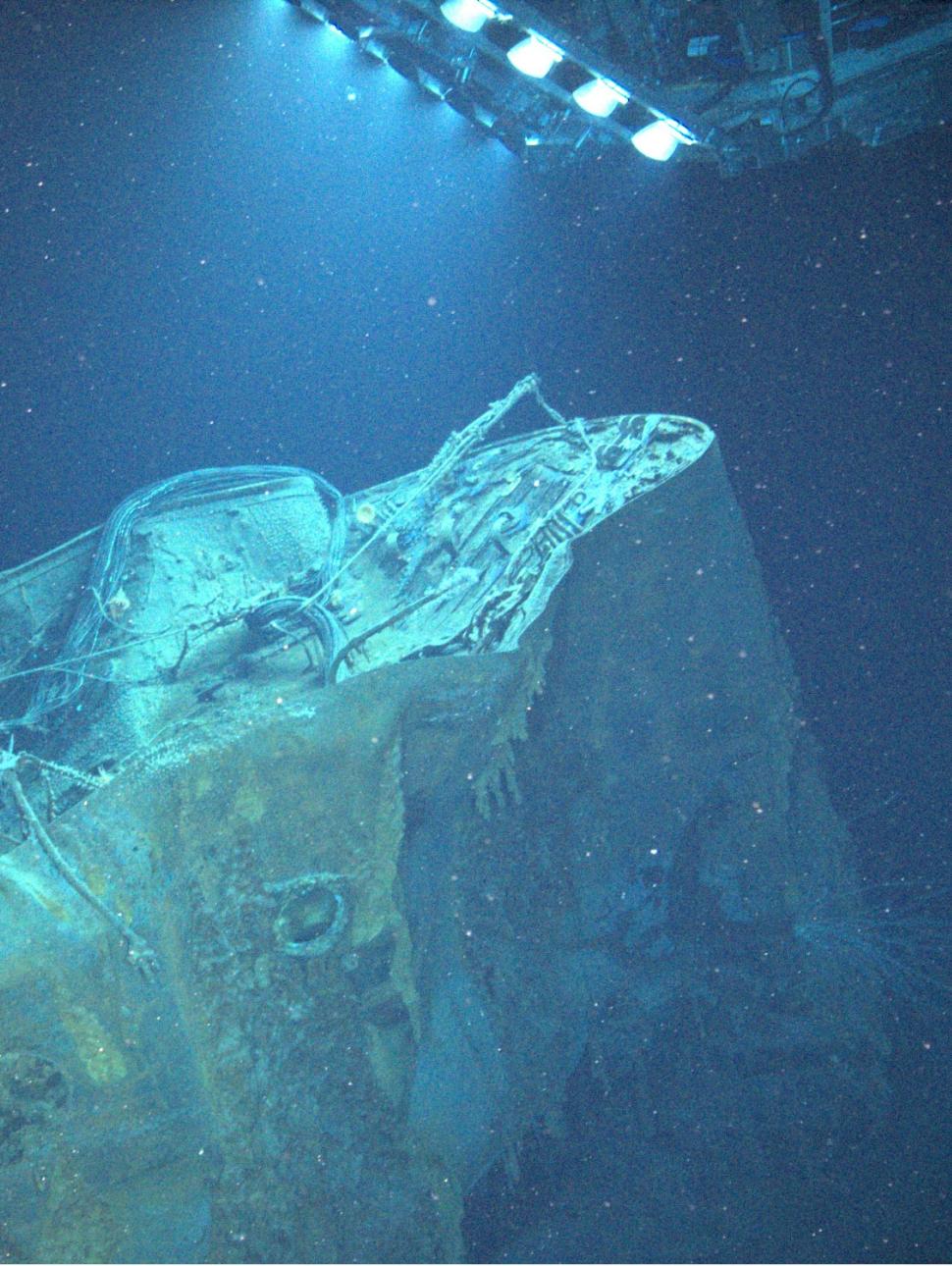 a shipwreck in the ocean with a remote operated vehicle shining a light on the wreck