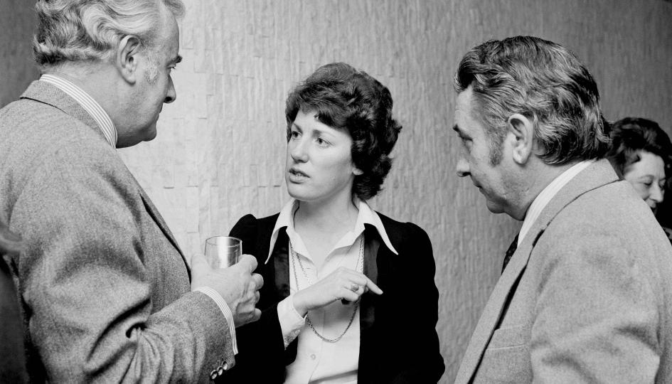 Black and white photograph of three people talking.