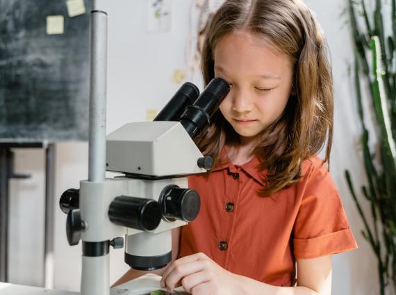 young child looking at a plant through a microscope 