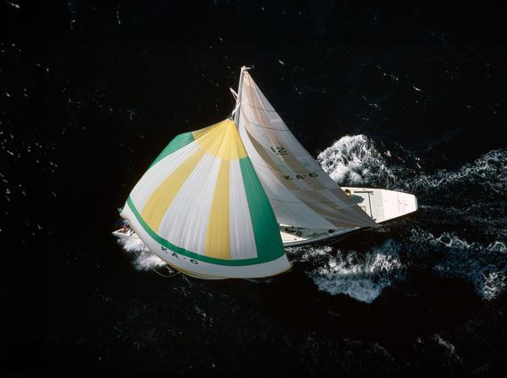 Overhead shot of a yacht with white, green and yellow colours sail in the water 