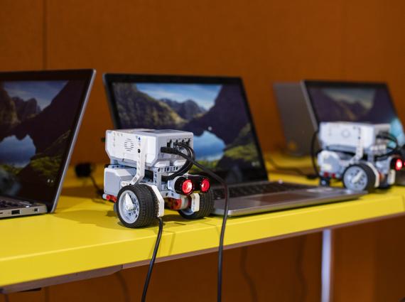 Technology linked to a laptop sits on a yellow desk