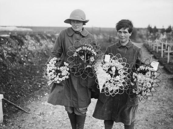 a black and white image of two women holding memorial flower wreath arrangements for 