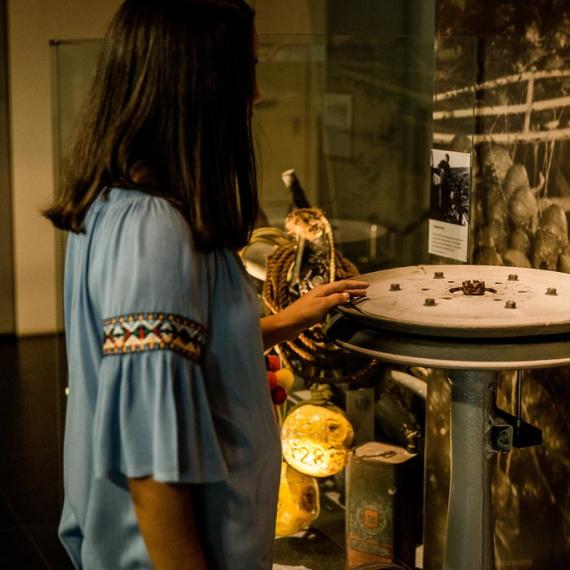 A person stands in a Museum gallery, touching an interactive exhibit