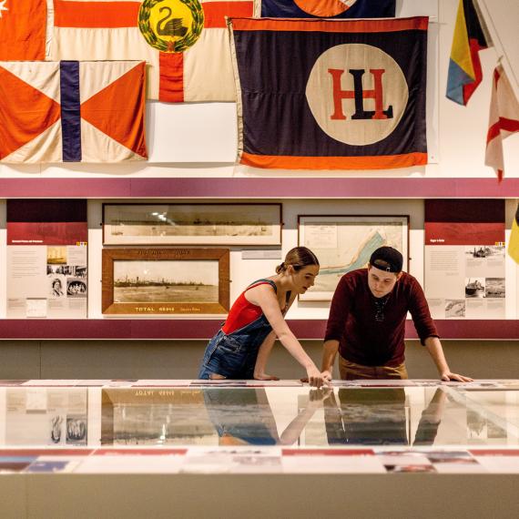 Two young people examine a huge tabletop map in a museum