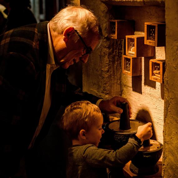 A child and older person examine an exhibit together in a museum gallery