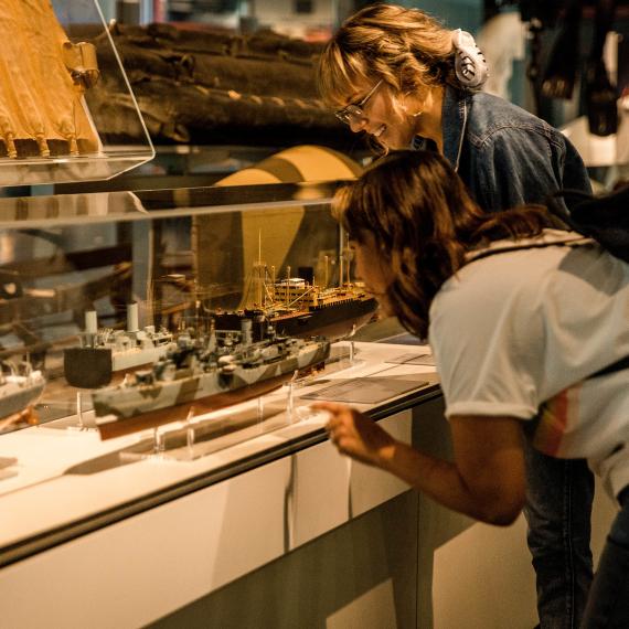 Two young people examine a showcase of model ships