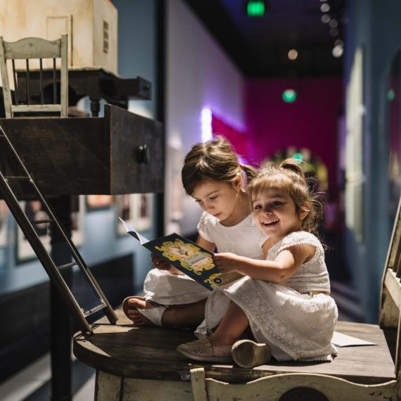 Two small children interact with a book in the Wonderland exhibition.