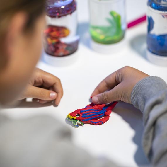 Hands assemble intricate piece of modelling with slow globe jars in the e background 