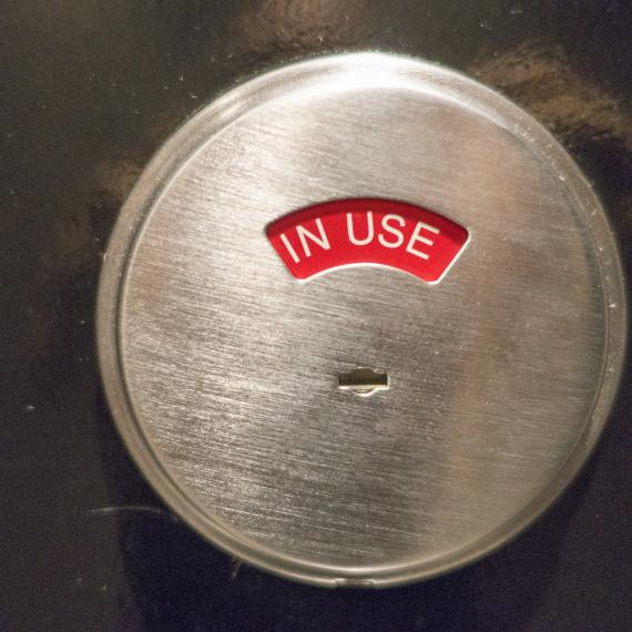 A silver toilet door lock turned to red reading 'occupied'