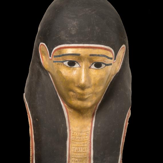 Ancient Egyptian artefact mask depicting lifelike features. golden face and black hair/headress