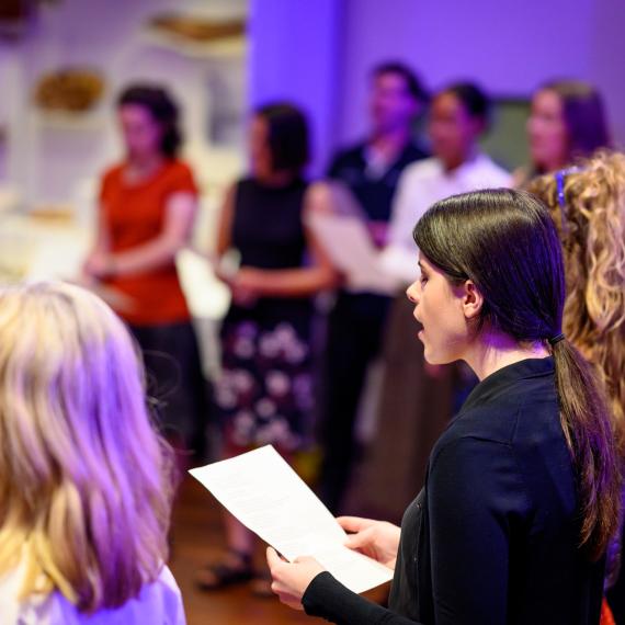 Many people standing singing in a room