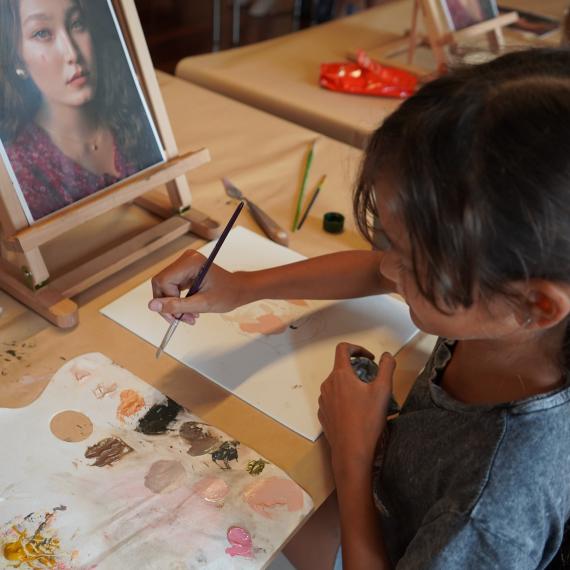 Image shows a young girl missing paint for a portrait she is painting