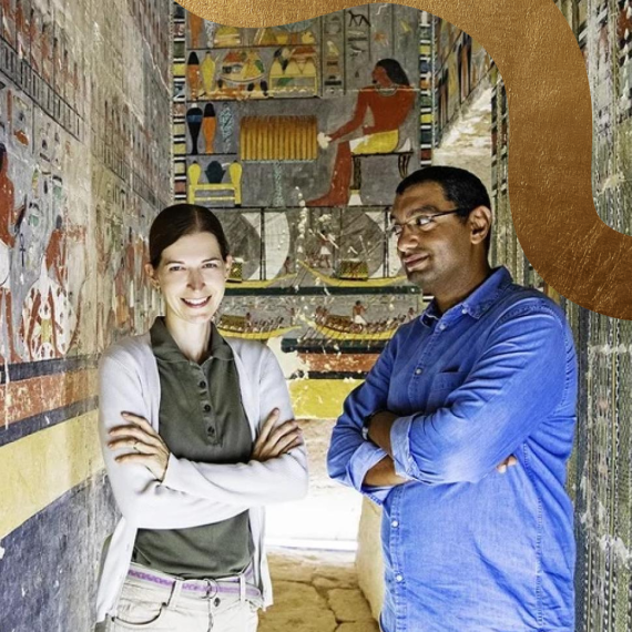 r. Mohamed Megahed and Dr. Hana Vymazalová stand side by side with their arms folded, facing the camera. They are situated inside an Egyptian tomb adorned with illustrations on the walls.