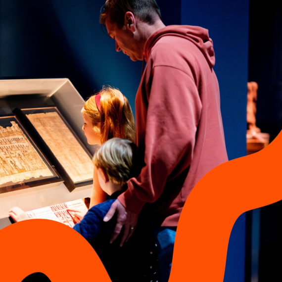 A family of three looking at pages from the Book of the Dead behind glass.