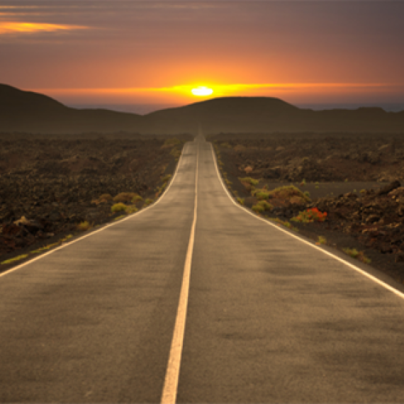 A road going into the distance with sun setting