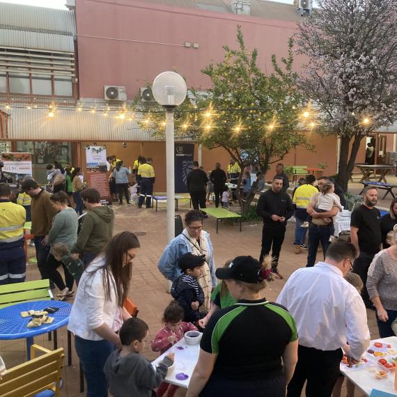A large crowd gather outdoors with stalls and tables with science activities