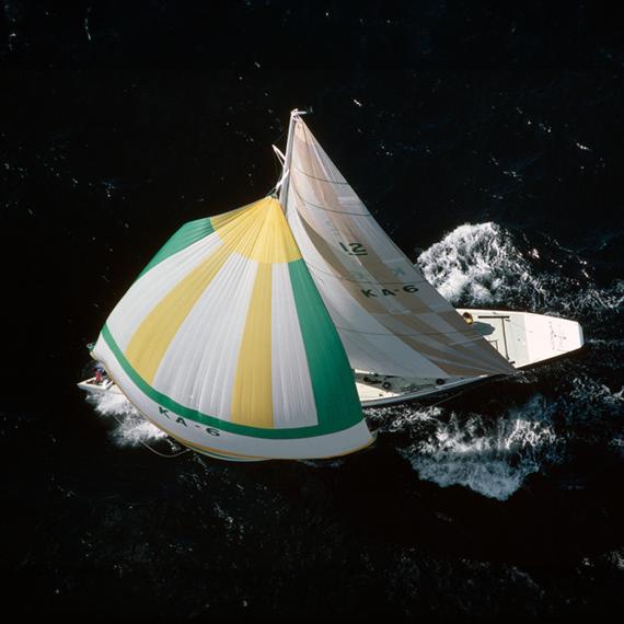 Overhead shot of a yacht with white, green and yellow colours sail in the water 