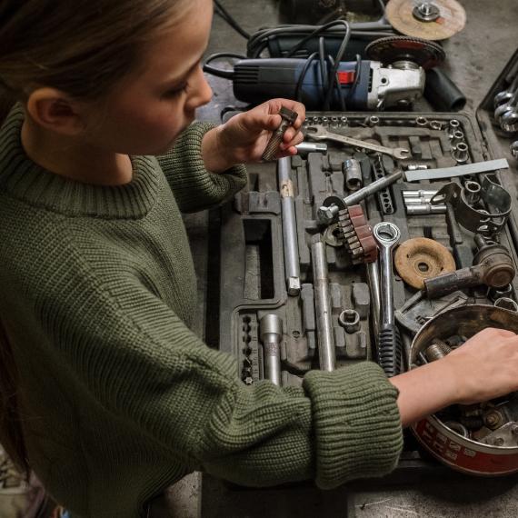 a young girl looks at various mechanics tools