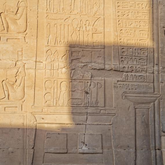 A sandstone wall carved with intricate depictions of surgical instruments in a classic Egyptian hieroglyphic style in the Temple of Kom Ombo
