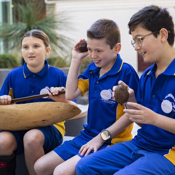 Three students hold Aboriginal artefacts 