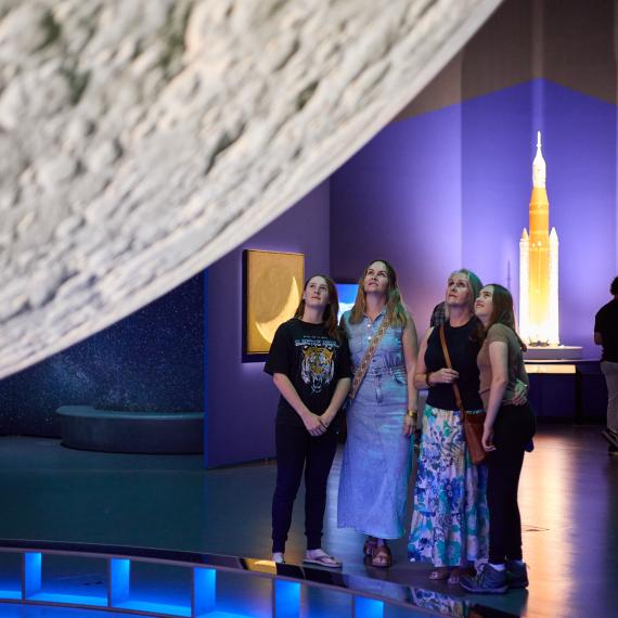 four women looking upward toward the moon