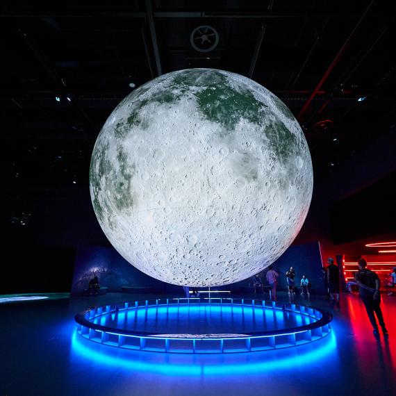 Large, impressive moon installation suspended in mid-air within an exhibition space