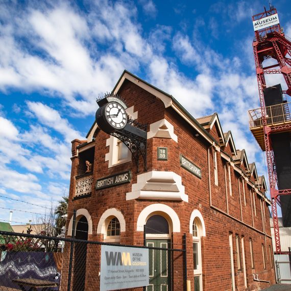 An old red brick building, the British Arms, stands beneath a large red tower