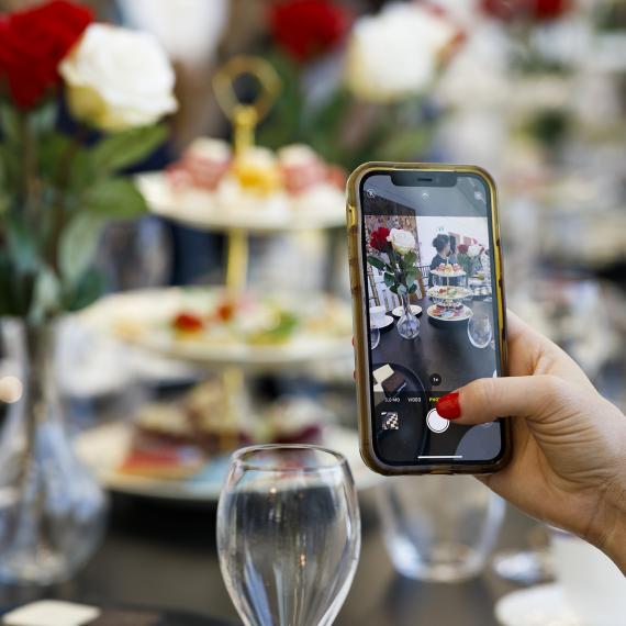 a high tea setup with someone using a phone camera and taking a picture 
