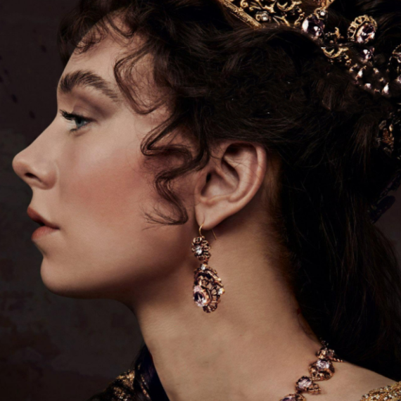 a profile of a woman wearing a crown and jewels with brown curly hair