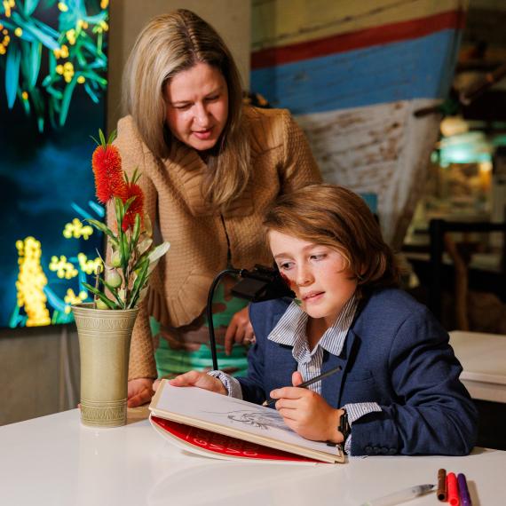an adult assists a child in using a drawing device on a table 