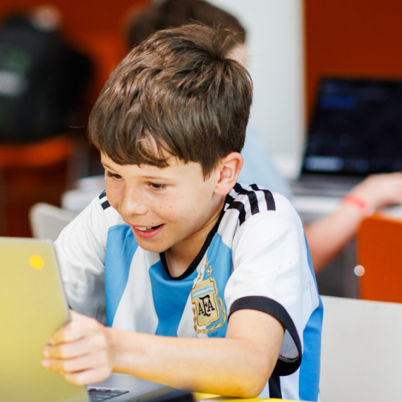 Kids happily participating in a computer program while wearing striped blue and white sports tops