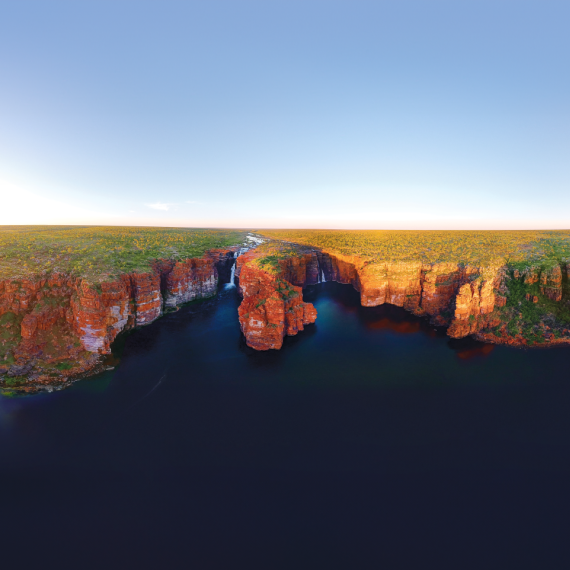 a landscape with ocean in the foreground and cliffs with waterfalls 