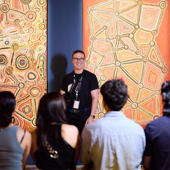 A museum staff members talking to visitor in an exhibition on a tour