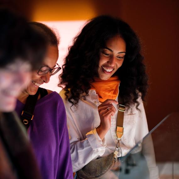 two women looking at exhibition showcase and smiling