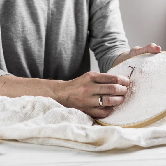 a close up of someone holding a fabric and stitching embroidery