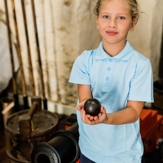 A young girl student holds an antique iron during a classroom session of the WA Shipwrecks Museum's education program Shipwrecked!