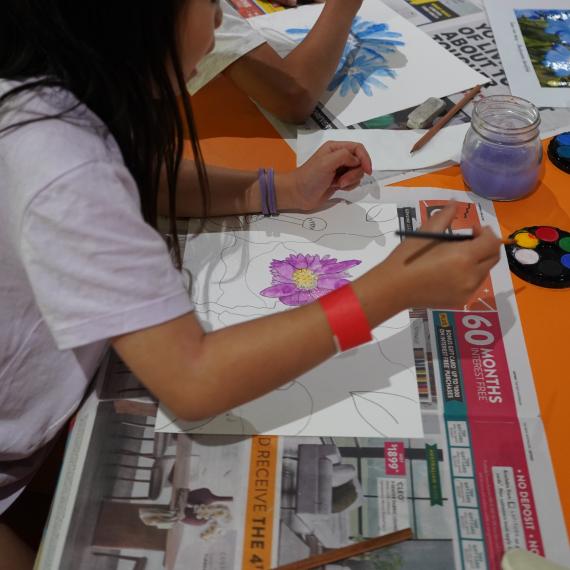 The photo shows two girls painting wildflowers using water colour paints .