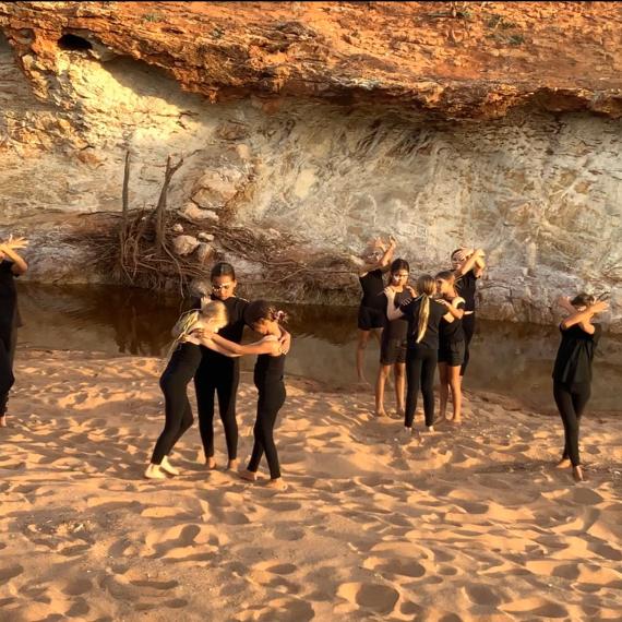 a group of young people stand in poses on the sand