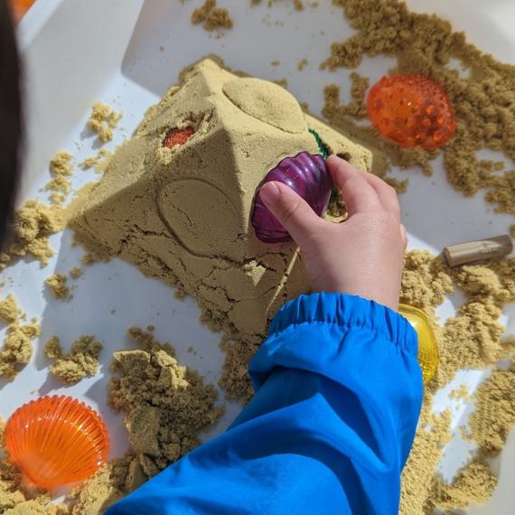 a overhead shot of a child creating a pyramid from sand 