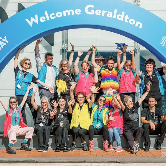 a group of happy people gather under an arch with words Welcome Geraldton