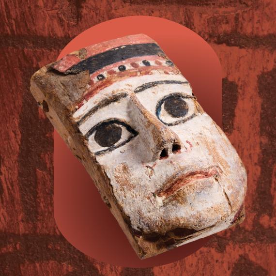 a painted mask object on a background of hieroglyphics