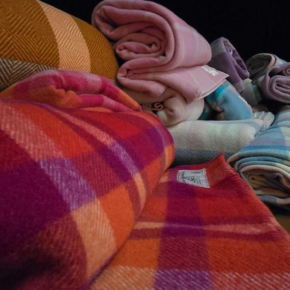 a pile of rolls of woollen fabrics of all colours 